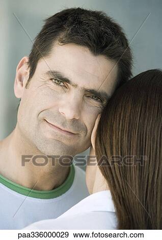 Stock Photo - Man resting head against woman's head, smiling, partial view. Fotosearch