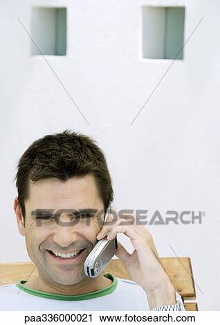 Man sitting and talking on cell phone, smiling, out-of-frame View Large Photo Image Stock Image - Man sitting and talking on cell phone, smiling, out-of-frame. Fotosearch