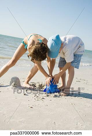 Boy and girl building sand castle together on beach View Large Photo Image Stock Photograph - Boy and girl building sand castle together on beach. Fotosearch