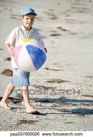Boy carrying beach ball on beach View Large Photo Image Stock Photograph - Boy carrying beach ball on beach. Fotosearch