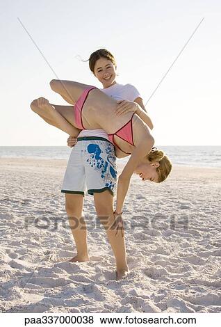 Stock Photo - Girl flipping sister over on beach. Fotosearch