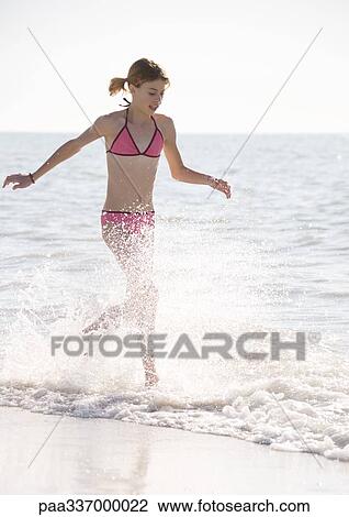 Girl running through surf on beach View Large Photo Image Stock Image - Girl running through surf on beach. Fotosearch