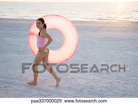 Girl running with innertube on beach View Large Photo Image Stock Photo - Girl running with innertube on beach. Fotosearch