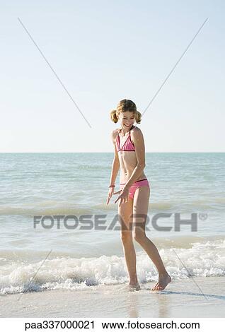 Girl standing in surf on beach View Large Photo Image Stock Image - Girl standing in surf on beach. Fotosearch