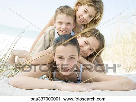 Stock Image - Kids lying on beach, portrait. Fotosearch