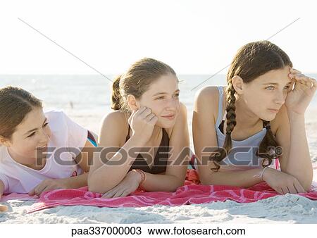 Stock Image - Three preteen girls lying on beach. Fotosearch