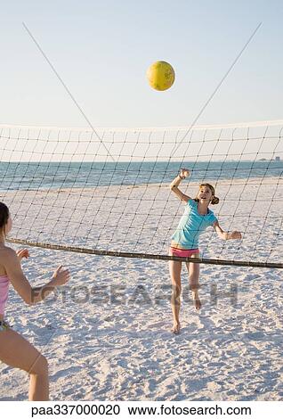 Stock Image - Two girls playing beach volleyball. Fotosearch