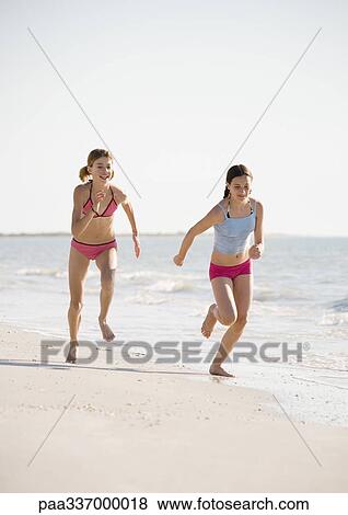 Stock Photo - Two preteen girls running on beach. Fotosearch