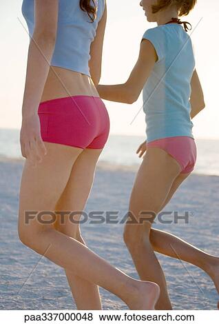 Stock Photo - Two preteen girls running on beach, cropped. Fotosearch