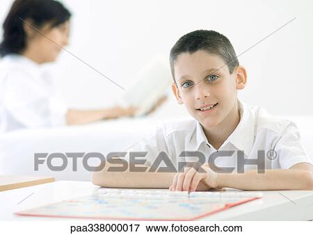 Boy sitting at board game, woman in background View Large Photo Image Stock Photo - Boy sitting at board game, woman in background. Fotosearch