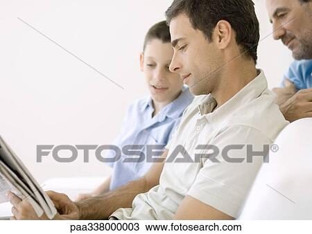 Stock Image - Man looking at newspaper with son and father. Fotosearch