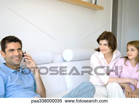 Man using cell phone while wife and daughter watch View Large Photo Image Stock Photography - Man using cell phone while wife and daughter watch. Fotosearch