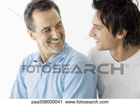 Young man and mature man smiling at each other View Large Photo Image Stock Image - Young man and mature man smiling at each other. Fotosearch