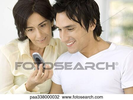 Young man and mother looking at cell phone View Large Photo Image Stock Image - Young man and mother looking at cell phone. Fotosearch