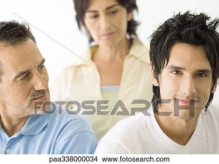 Picture - Young man, parents looking at him. Fotosearch