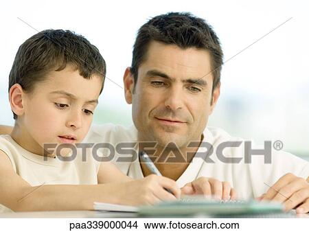 Boy doing homework with father's help, cropped View Large Photo Image Picture - Boy doing homework with father's help, cropped. Fotosearch