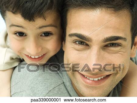 Stock Image - Father and son smiling, close-up of faces. Fotosearch