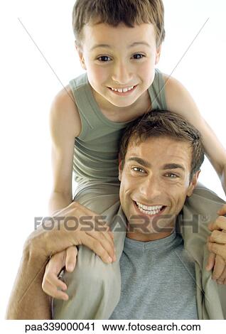 Man with son sitting on shoulders, smiling View Large Photo Image Stock Image - Man with son sitting on shoulders, smiling. Fotosearch