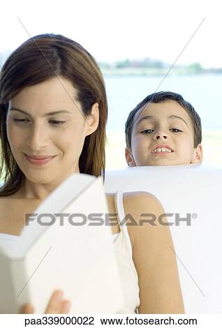 Stock Image - Woman reading book while boy looks over shoulder. Fotosearch