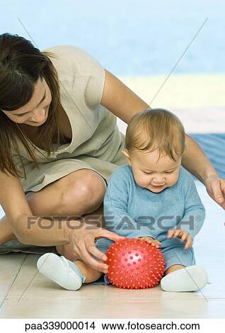 Picture - Woman sitting on floor playing with baby. Fotosearch