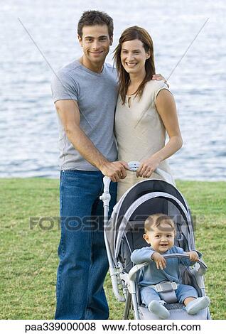 Stock Photo - Young couple standing with baby in stroller. Fotosearch