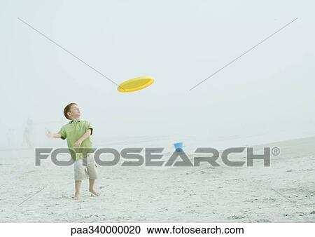 Stock Image - Boy playing frisbee on beach. Fotosearch