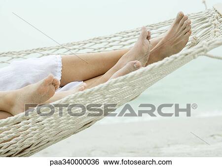 Stock Photograph - Family lying in hammock together, close-up of feet. Fotosearch