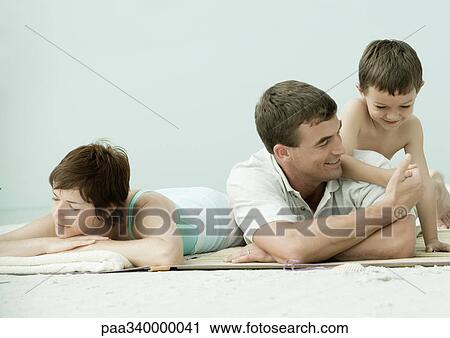 Family lying on beach, man and son thumb wrestling while mother sleeps View Large Photo Image Stock Image - Family lying on beach, man and son thumb wrestling while mother sleeps. Fotosearch
