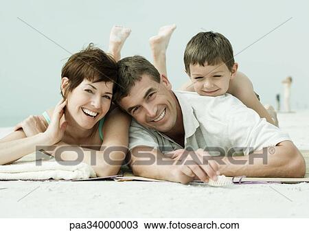 Stock Image - Family lying on beach, portrait. Fotosearch
