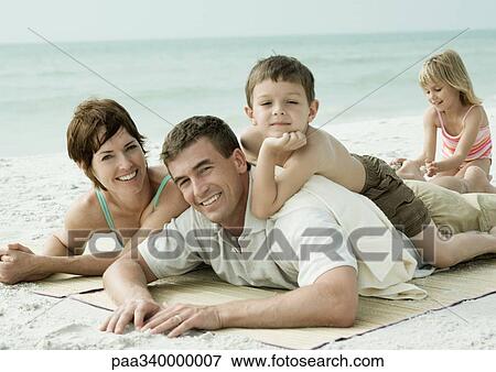 Stock Photo - Family lying on beach, smiling. Fotosearch