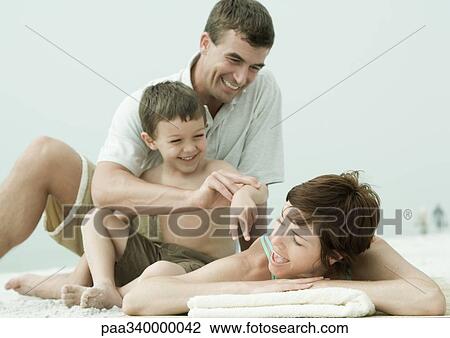 Family on beach, man and son bothering woman while she's lying down View Large Photo Image Stock Image - Family on beach, man and son bothering woman while she's lying down. Fotosearch