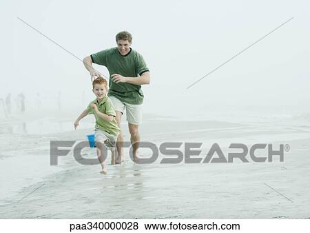 Man chasing son on beach View Large Photo Image Stock Photo - Man chasing son on beach. Fotosearch