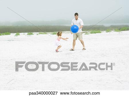 Man playing ball with daughter on sand View Large Photo Image Stock Photo - Man playing ball with daughter on sand. Fotosearch