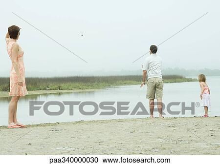 Man throwing pebble into water while family watches View Large Photo Image Stock Image - Man throwing pebble into water while family watches. Fotosearch