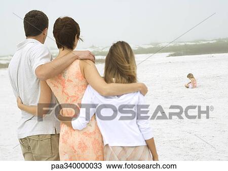 Parents and teenage daughter watching little girl play in sand in distance View Large Photo Image Stock Image - Parents and teenage daughter watching little girl play in sand in distance. Fotosearch