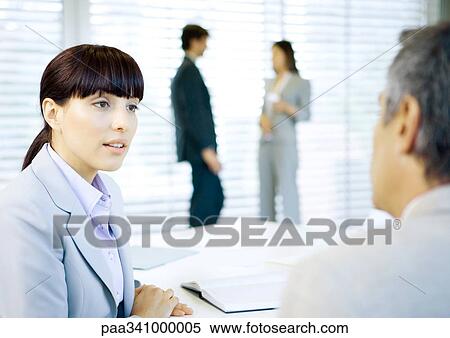 Business colleagues conversing in office View Large Photo Image Stock Photography - Business colleagues conversing in office. Fotosearch