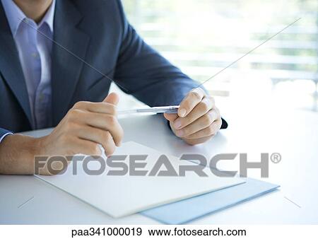 Stock Photo - Businessman holding pen, cropped view of hands. Fotosearch