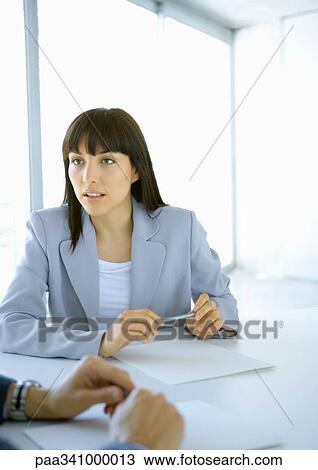 Businesswoman sitting at table looking attentively toward colleague View Large Photo Image Stock Image - Businesswoman sitting at table looking attentively toward colleague. Fotosearch