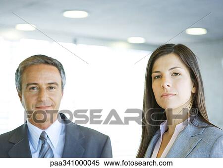 Stock Photography - Mature businessman and young businesswoman, looking at camera. Fotosearch