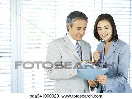 Two business colleagues looking at document together View Large Photo Image Stock Image - Two business colleagues looking at document together. Fotosearch