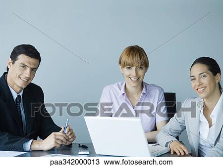 Business colleagues gathered around laptop, smiling View Large Photo Image Stock Image - Business colleagues gathered around laptop, smiling. Fotosearch