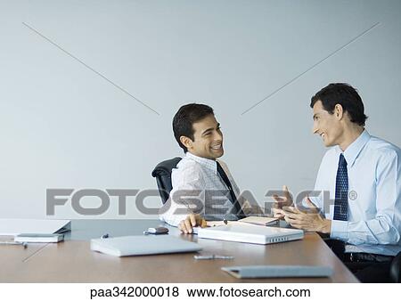 Stock Photo - Business colleagues having conversation, smiling. Fotosearch