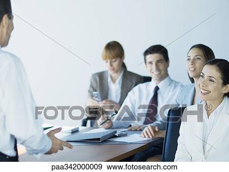 Stock Photo - Business colleagues in meeting, smiling. Fotosearch