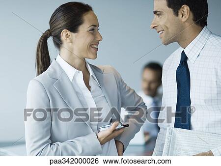 Business colleagues standing face to face, smiling View Large Photo Image Stock Photograph - Business colleagues standing face to face, smiling. Fotosearch