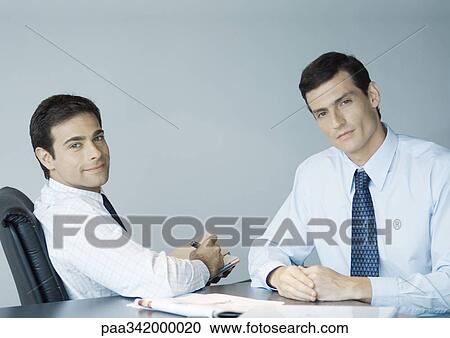 Stock Image - Business colleagues working together, smiling at camera. Fotosearch