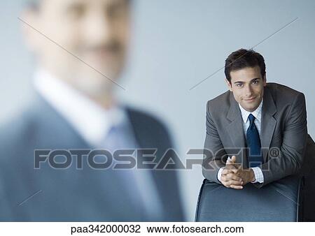 Businessman leaning on back of chair, focus on background View Large Photo Image Stock Image - Businessman leaning on back of chair, focus on background. Fotosearch