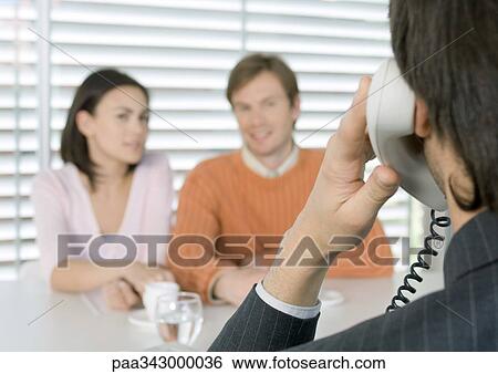 Businessman using phone while couple waits View Large Photo Image Stock Photograph - Businessman using phone while couple waits. Fotosearch