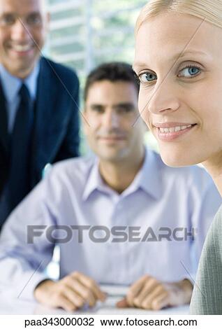 Businesswoman smiling at camera, colleagues in background View Large Photo Image Stock Image - Businesswoman smiling at camera, colleagues in background. Fotosearch