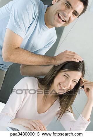 Stock Image - Couple laughing, man with hands on woman's head. Fotosearch
