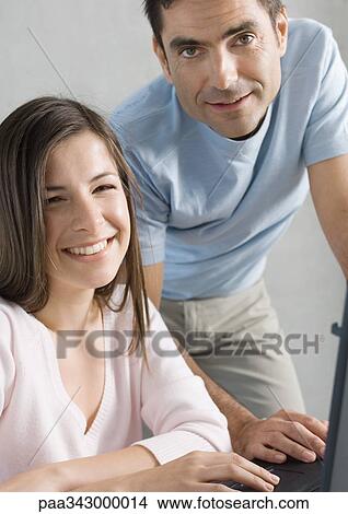 Picture - Couple using laptop, smiling. Fotosearch